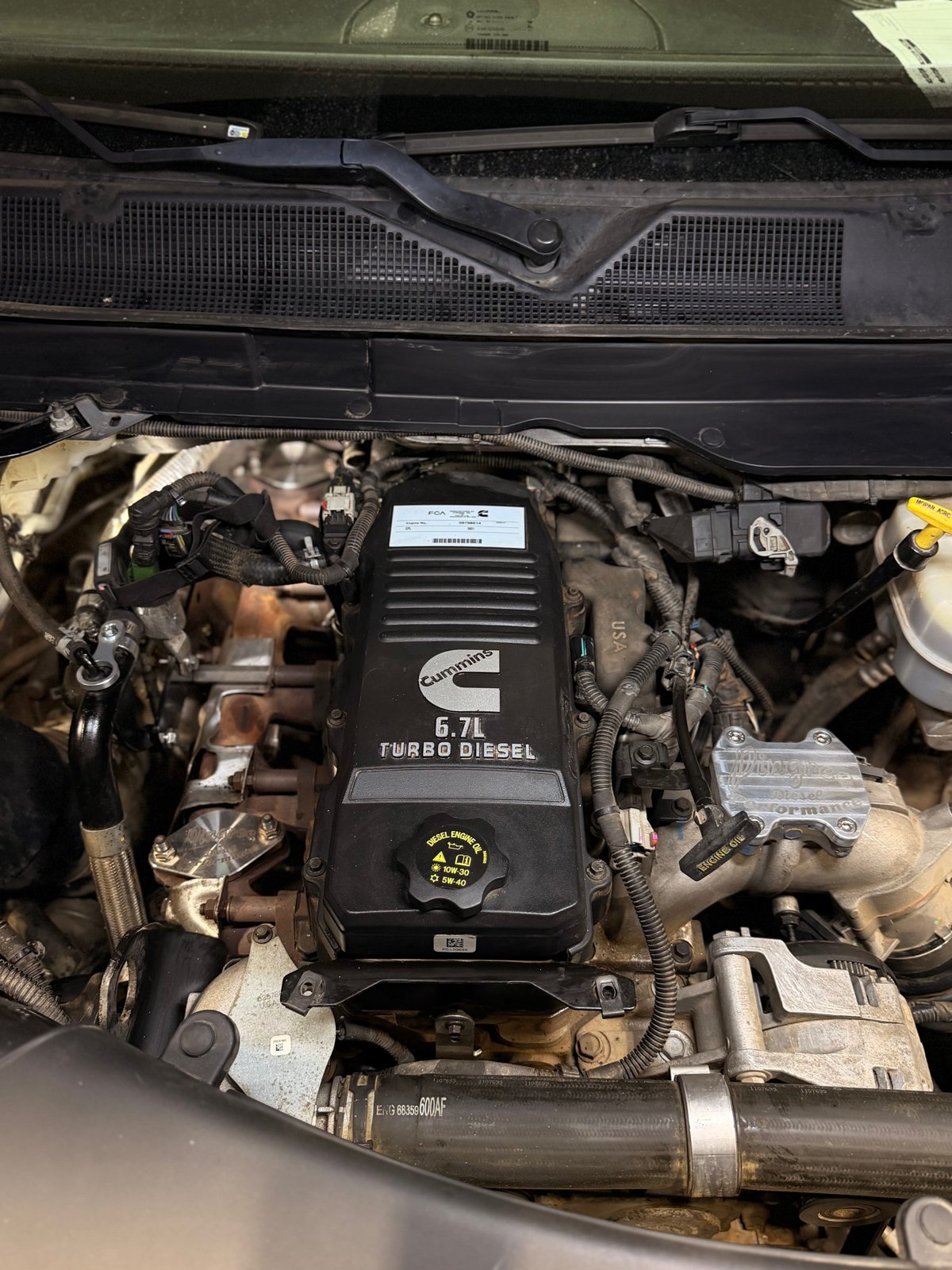 Engine bay with a cover marked Cummins 6.7L Turbo Diesel.